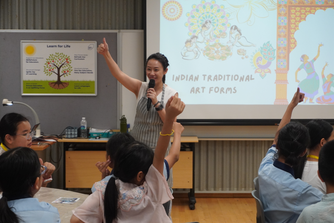 Students raising their hands during a presentation on Indian traditional art forms.